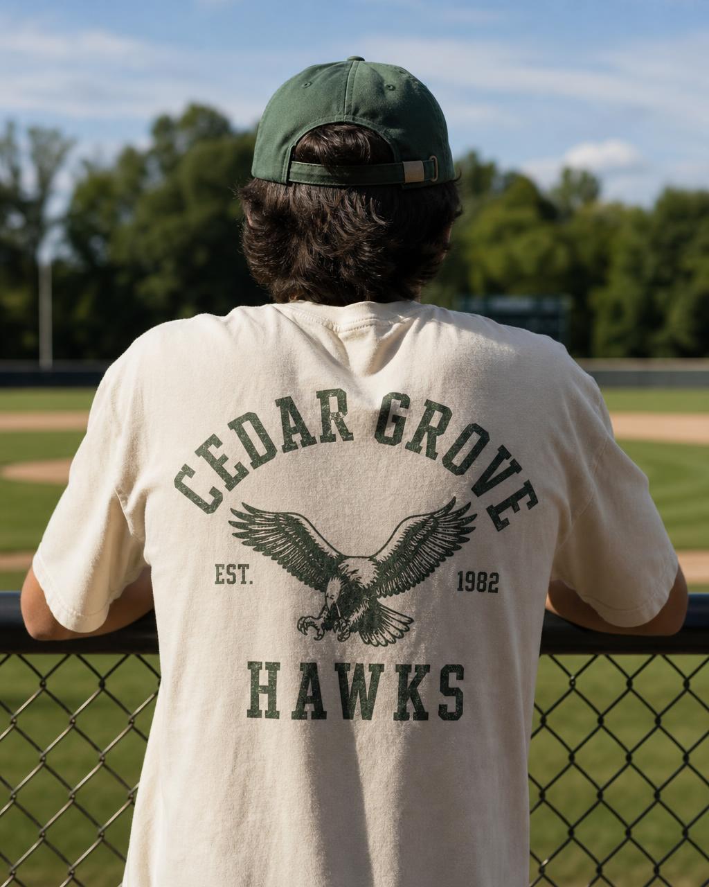 Cream vintage-washed tee with an arched Cedar Grove Hawks crest print